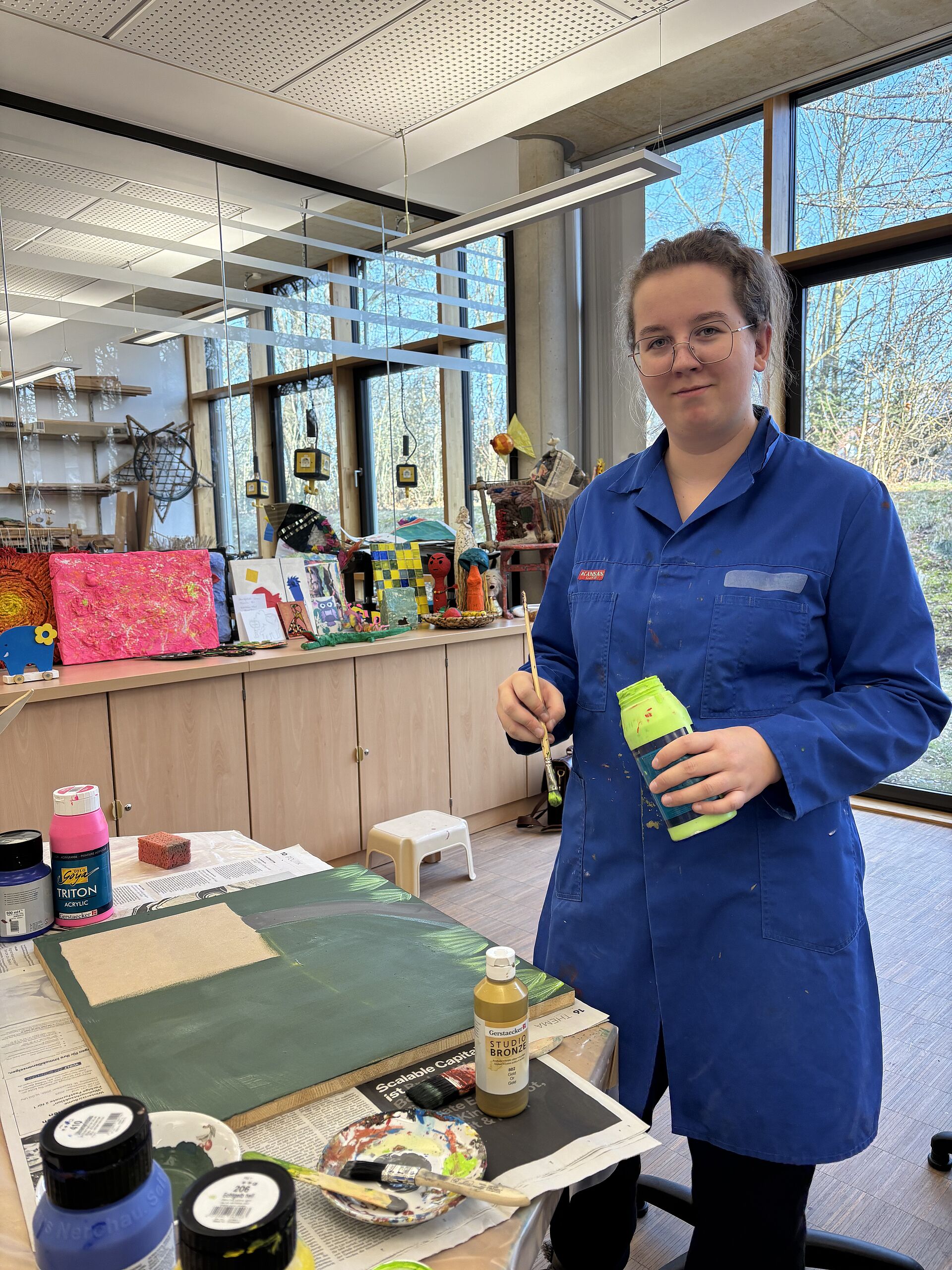 Schülerin bemalt eine Holzplatte